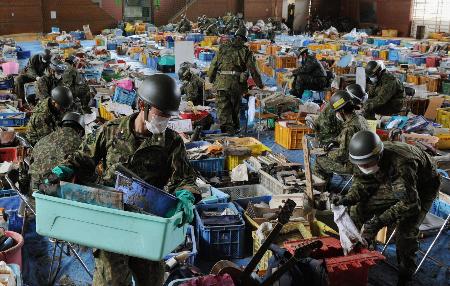 宮城県山元町の小学校には、津波により持ち主が不明となった写真や位牌、ランドセルなどが大量に保管されていた。自衛隊員が思い出の品に付いた泥やほこりを丁寧に落としていた＝２０１１年４月