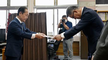 米軍ヘリの緊急着陸を受け、防衛省沖縄防衛局の村井勝局長（右）に抗議文書を手渡す沖縄県名護市の渡具知武豊市長＝９日午前、名護市役所