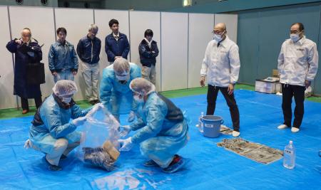 京都府などが宇治市で実施した避難所の運営訓練で、吐しゃ物の処理方法を学ぶ市職員ら＝１０日午後