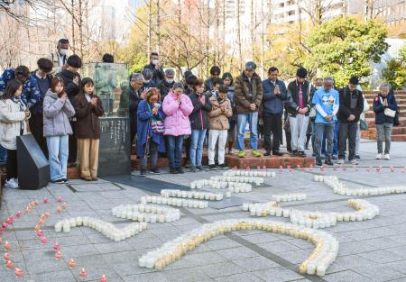 東日本大震災の発生時刻に合わせて黙とうする人たち＝１１日午後、神戸市中央区の東遊園地