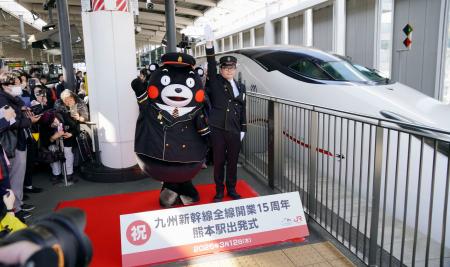 　九州新幹線全線開業１５周年を記念した出発式で、出発の合図を送る熊本県ＰＲキャラクター「くまモン」ら＝１２日午前、ＪＲ熊本駅