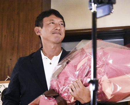 熊本県八代市長選で初当選を果たし、花束を手に笑顔の小野泰輔氏＝２０２５年８月、八代市