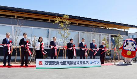 JR双葉駅前に完成した商業施設のオープニングセレモニーで、テープカットする伊沢史朗町長(左から4人目)ら=14日午前、福島県双葉町