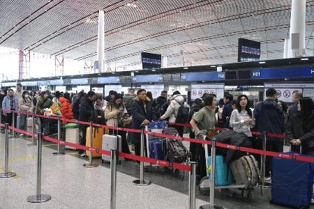 春節に合わせた大型連休の初日、北京首都国際空港で日本便などをあつかうカウンターにならぶ人たち＝２月１５日