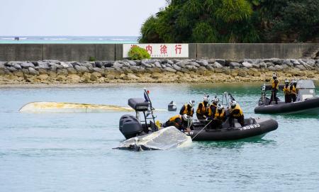 転覆した船２隻をえい航する海上保安庁の職員ら＝１６日午後１時２６分、沖縄県名護市の辺野古漁港