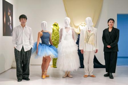 衣装を着たダンサーと並ぶ堀内将平さん(左端)と井上ユミコさん(右端)=東京都渋谷区