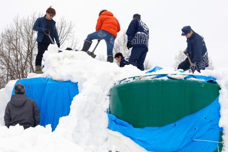 雪山からタンクを掘り出す高砂酒造の社員ら＝１９日午前、北海道美瑛町