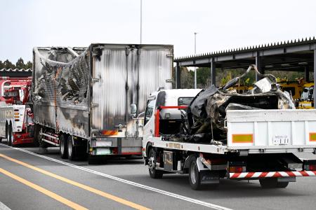 事故があった新名神高速下り線の野登トンネルから運び出された焼けたトラックと車両(荷台上)=20日午後0時23分、三重県菰野町