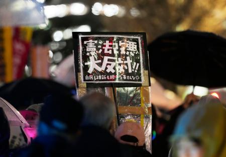 国会前でプラカードを掲げ、憲法改正の動きなどに抗議する人たち＝２５日夜