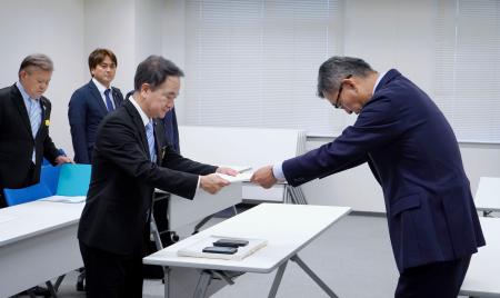 防衛省沖縄防衛局の村井勝局長（右）に意見書を手渡す沖縄県宜野湾市議会の呉屋等議長＝２６日午後、嘉手納町