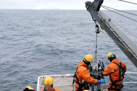 氷山が浮く海から観測機器を引き揚げるしらせ乗員＝２６日、南極海・トッテン氷河沖（南極観測隊同行記者）