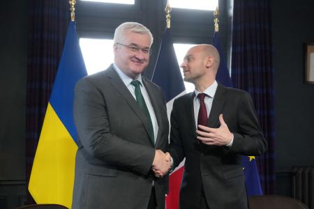 握手するフランスのバロ外相(右)とウクライナのシビハ外相=26日、フランス・セルネラビル(ロイター=共同)