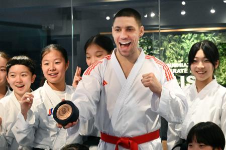 返還された銅メダルを手に、笑顔で写真に納まるスタニスラフ・ホルナさん＝５日、東京都港区