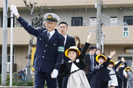 新１年生と手をつないで横断歩道を渡る警視庁の筒井洋樹警視総監（手前左）＝６日午後、東京都大田区