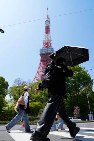 今年初の夏日となった東京都心部で、日傘を差して歩く人=11日午後、東京都港区
