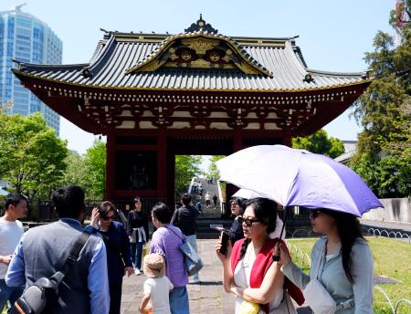 今年初の夏日となった東京都心部で日傘を差して歩く人たち=11日午後、東京都港区