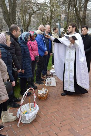 キーウの聖ソフィア大聖堂で、市民に聖水をかける聖職者(右手前)=12日(共同)