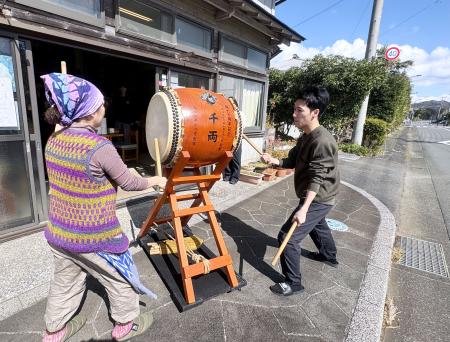 　青空の下、店先で八丈太鼓を演奏する渡辺志保さん（左）と晴万さん＝東京都八丈町