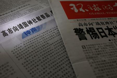 靖国神社に「真榊」を奉納した高市首相を批判する評論を掲載した、２２日付の中国共産党機関紙、人民日報。右は１面トップで報じる環球時報（共同）