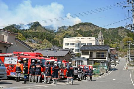 避難所となっている吉里吉里学園小学部(奥)近くから立ち上る煙=24日午前、岩手県大槌町
