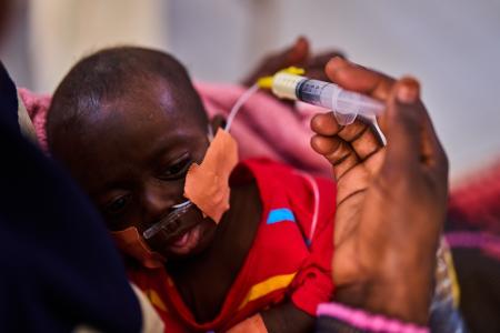 １５日、スーダン北東部ポートスーダンで、母親から粉ミルクを与えられる栄養失調の幼児（ＡＰ＝共同）