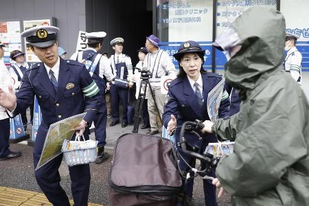 　１６歳以上の自転車の交通違反に反則金納付を通告できる交通反則切符（青切符）制度が始まり、東京都北区の交差点付近で利用者に指導する警察官＝１日