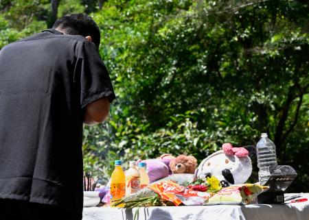 女性の遺体が見つかった現場で手を合わせる父親＝２８日午前、沖縄県恩納村
