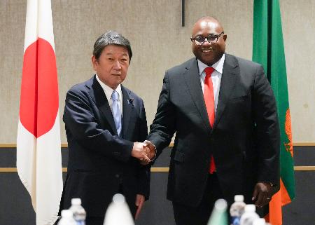 訪問先のザンビアでハインベ外相（右）と握手する茂木外相＝３０日（外務省提供）
