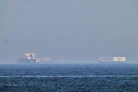 １日、ホルムズ海峡に近いオマーン湾に停泊するタンカー（左）（ＡＰ＝共同）