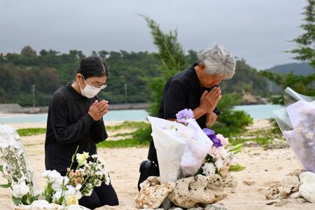 転覆事故現場を臨む浜で手を合わせる「ヘリ基地反対協議会」の仲村善幸共同代表（右）ら＝３日午前、沖縄県名護市