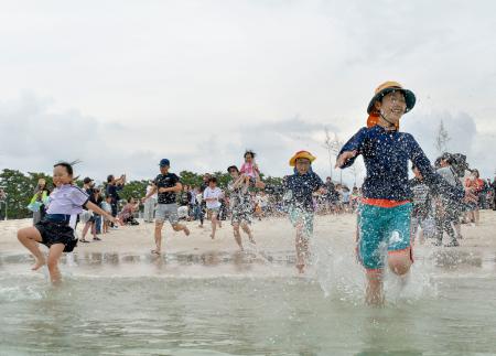 　和歌山県白浜町の白良浜が海開きし、海へ駆け込む海水浴客＝３日午前