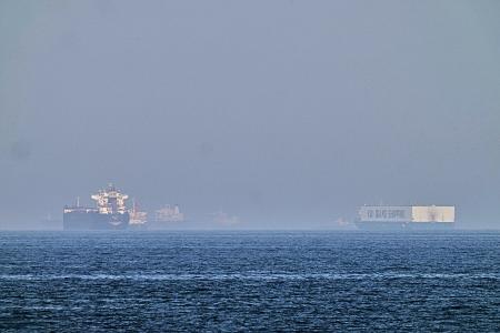 １日、ホルムズ海峡に近いオマーン湾に停泊するタンカー（左）（ＡＰ＝共同）