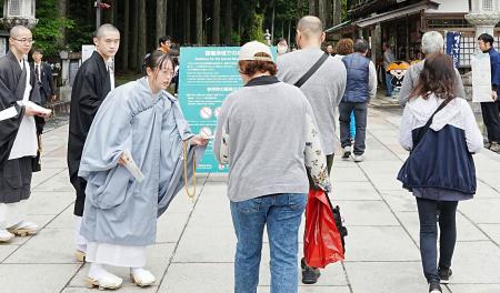 　高野山の金剛峯寺の奥之院入り口で、肩や足の露出が多い服装を控えるよう啓発する僧侶ら＝６日午前、和歌山県高野町