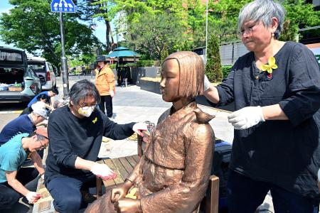 ６日、韓国・ソウルで慰安婦問題を象徴する少女像の保守作業に当たる彫刻家の金曙ギョンさん（右）ら（共同）