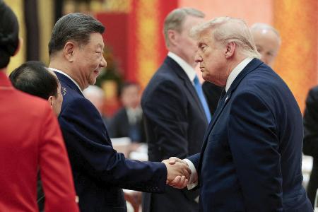夕食会で握手するトランプ米大統領（右）と中国の習近平国家主席＝１４日、北京の人民大会堂（ロイター＝共同）