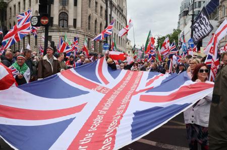 16日、ロンドンで極右活動家が主催したデモに参加し、英国旗を広げる人たち(共同)