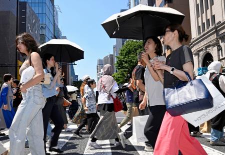 日傘を差して東京・銀座を歩く人たち。都心は今年初の真夏日となった=17日午後