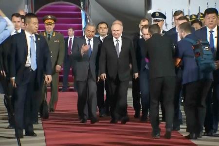 北京に到着し、中国の王毅外相（中央左）に付き添われるロシアのプーチン大統領（同右）＝１９日（ＡＰ＝共同）