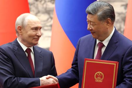 調印式で握手するロシアのプーチン大統領(左)と中国の習近平国家主席=20日、北京の人民大会堂(共同)