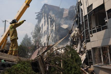 22日、ロシアが実効支配するウクライナ東部ルハンスク州スタロビルスクで、ウクライナによる攻撃で破壊された建物からがれきを撤去する救急隊(タス=共同)