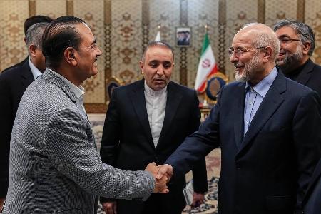 23日、イランの首都テヘランで、ガリバフ国会議長(右)と握手するパキスタンの軍トップ、ムニール陸軍元帥(イラン国会議長事務所提供・ゲッティ=共同)
