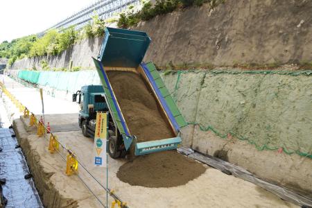 低レベル放射性廃棄物埋設センターで初めてとなる覆土作業をするトラック＝２５日午前、青森県六ケ所村