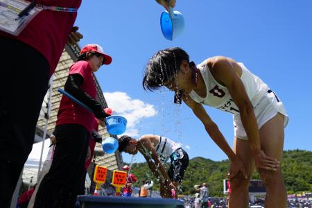 全国高校総体の陸上競技で、冷水をかけてもらう選手たち＝２０２５年７月、広島市