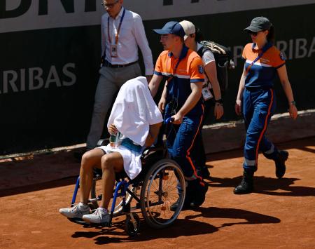 女子シングルス１回戦の第３セットで途中棄権し、車いすで運ばれる内島萌夏（手前）＝パリ（共同）