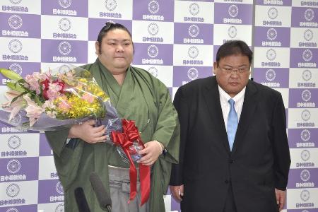 引退記者会見を終え花束を手にする元幕内剣翔。右は追手風親方＝４月、東京・両国国技館