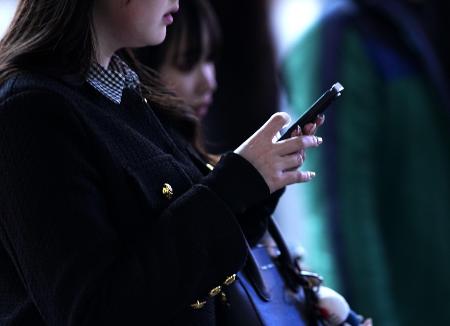 東京・渋谷のスクランブル交差点で、スマートフォンを手にする人＝２０２５年２月