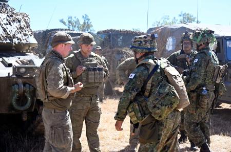 ２９日、日米豪３カ国の定例訓練「サザン・ジャッカルー」の開会式後、オーストラリア軍の兵士らと言葉を交わす陸上自衛隊員（右）＝オーストラリア・タウンズビル郊外（共同）