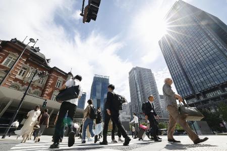 強い日差しの中、ＪＲ東京駅前を歩く人たち