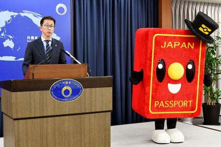 記者会見する北村俊博外務報道官とパスポートのイメージキャラクター「パスポくん」＝５月、外務省