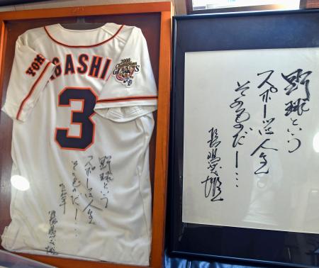 石井彰英さんが所有する、長嶋さんのサイン入りユニホーム（左）と座右の銘を記した直筆の色紙＝５月、東京都内